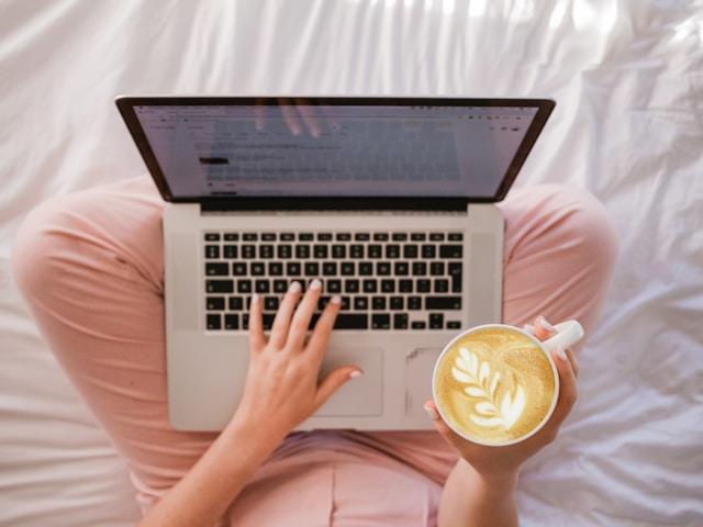women holding a cup of coffee above computer